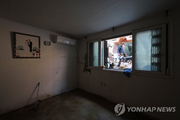 지난 12일 오후 서울 관악구 신림동 일대 반지하에 걸린 부부의 사진 옆 창문에 폭우로 침수된 물품들이 널부러져 있다.